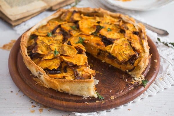 A straight view of sweet potato puff pastry pie with balsamic onions on top.