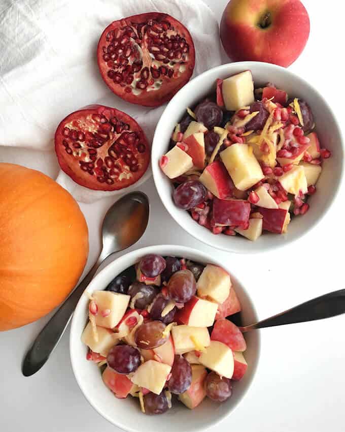An overhead view of a two-bowl meal full of healthy fall fruit salad with creamy dressing.