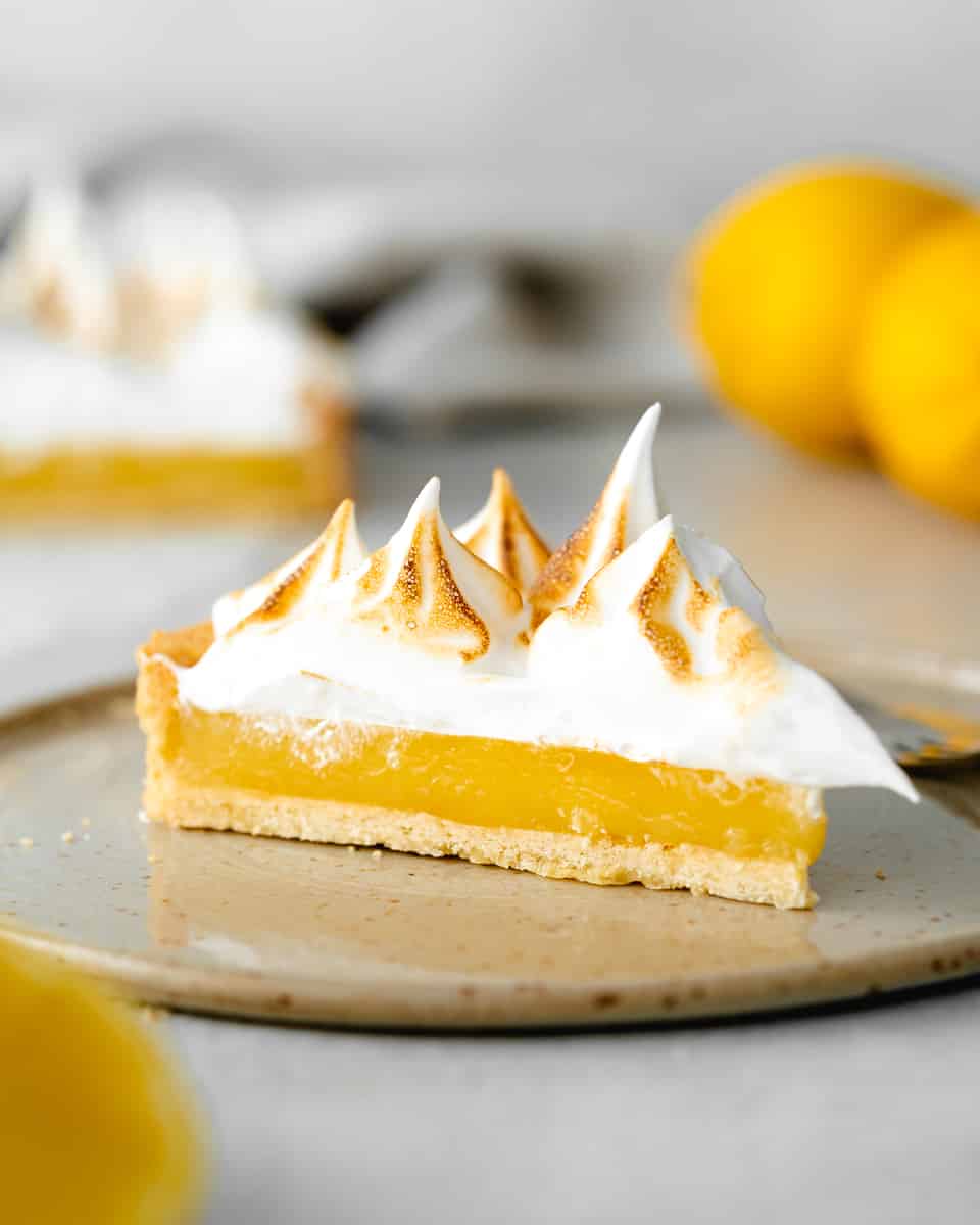 A straight view of a slice of vegan lemon meringue pie placed on a plate.