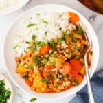 An overhead image of vegan massaman curry served on a plate with rice.