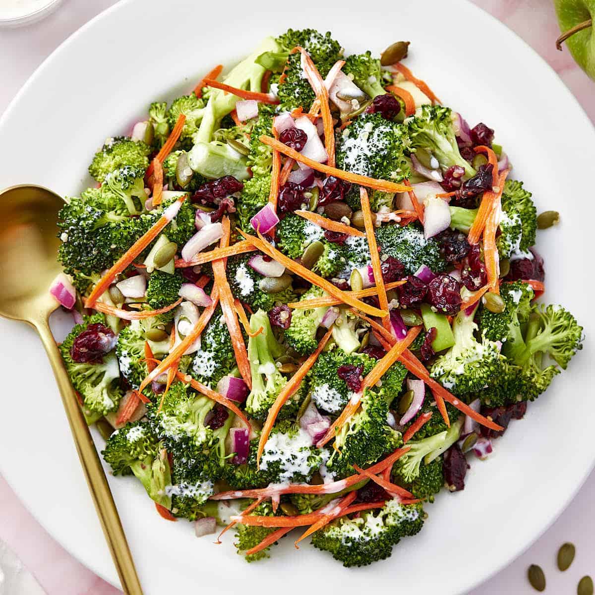 Overhead view of vegetarian raw broccoli salad with greek yogurt placed on a white platter.