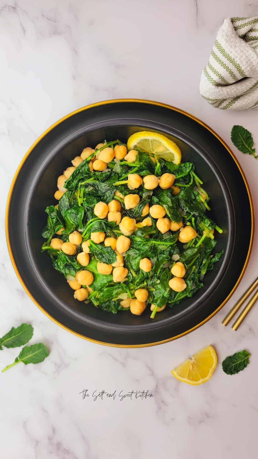 Overhead view of a warm kale salad with chickpeas placed on a black serving dish.